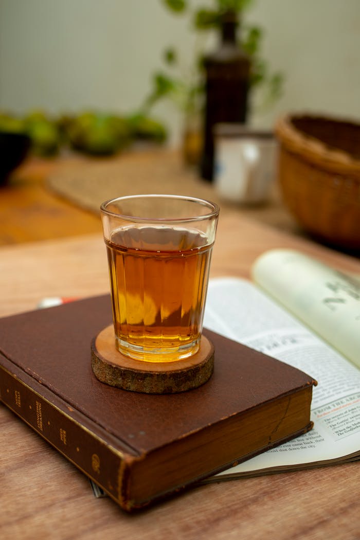 A warm glass of tea rests on an old book, creating a cozy and inviting atmosphere.