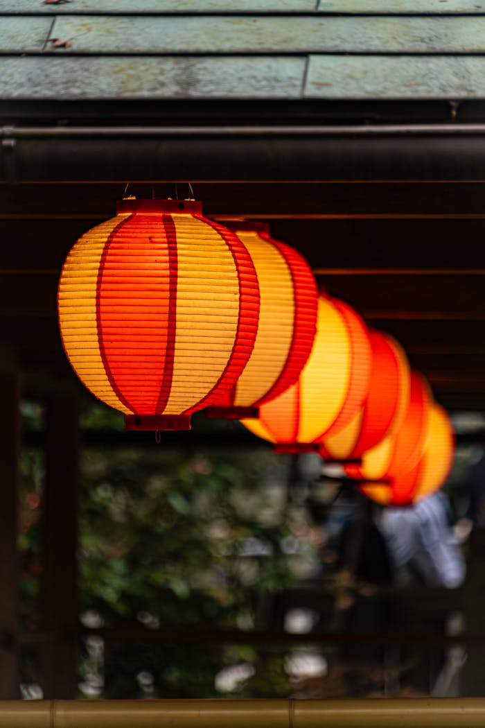 Bright red and orange lanterns line the roof of a Kyoto temple, adding a vibrant touch.